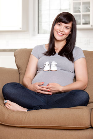 Pregnant woman with baby shoes on her stomach