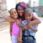 A mother and 2 children smiling